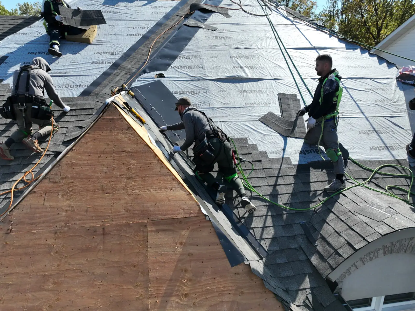 Roofing crew on an Oakville roof with grey shingles, exposed plywood and silver underlayment