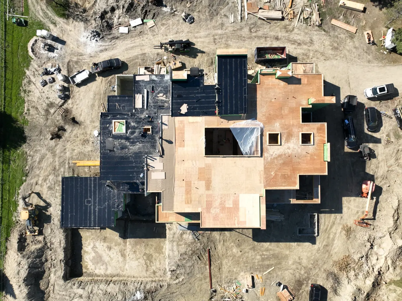 Top-down drone view of a Brampton building under construction, showing exposed plywood roof decking, black roof membrane and roof openings