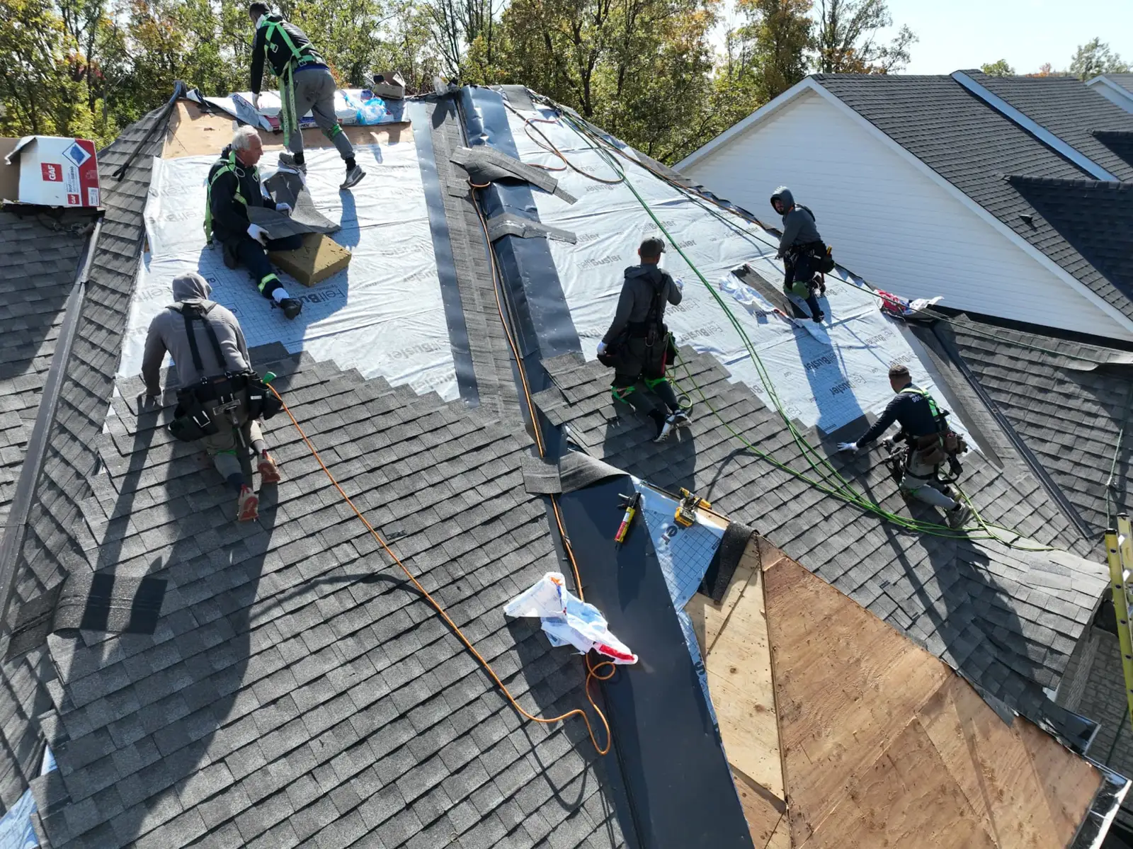 Drone view of an Oakville roofing crew installing grey shingles on both sides of a ridge