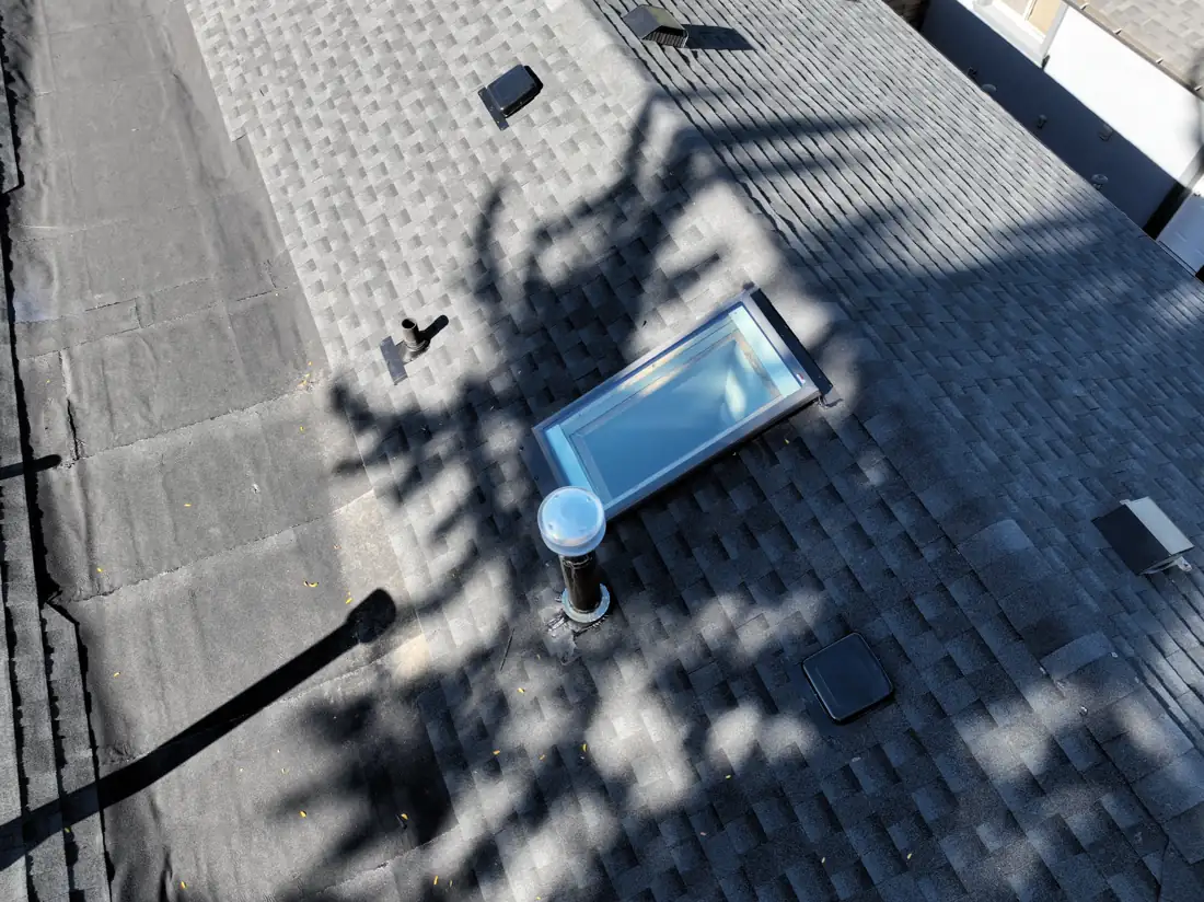 Close-up of the skylight, vent stack and new shingles on the completed Bonnymede Drive roof