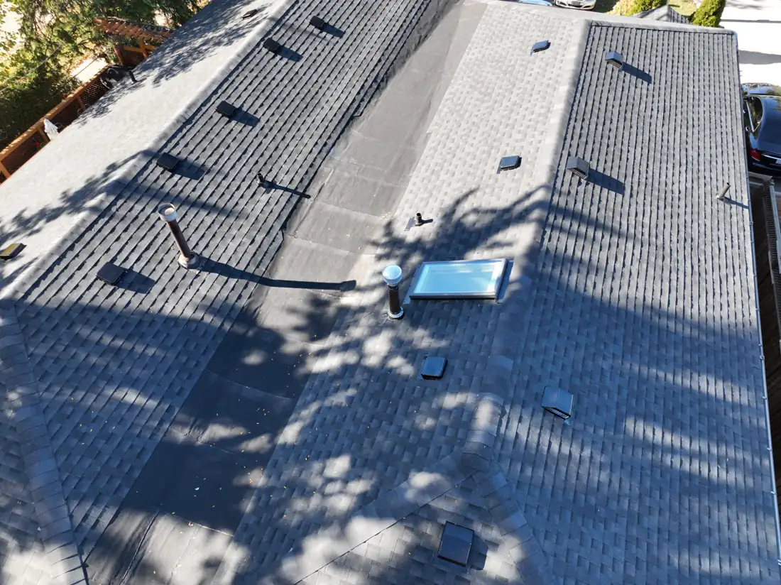 Close aerial view of new shingles around the skylight, plumbing vents and roof vents on the Bonnymede Drive roof