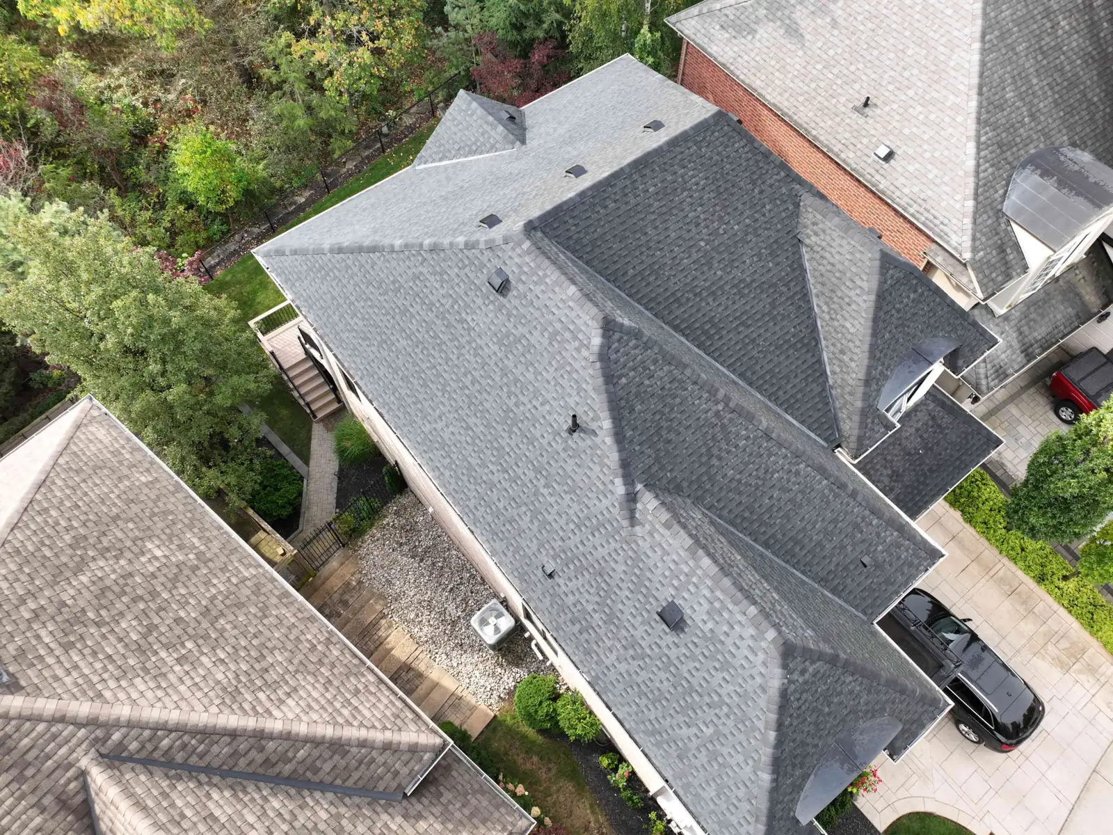 Overhead drone view of a newly installed dark shingle roof on an Oakville home, showing ridge caps, box roof vents and pipe flashings